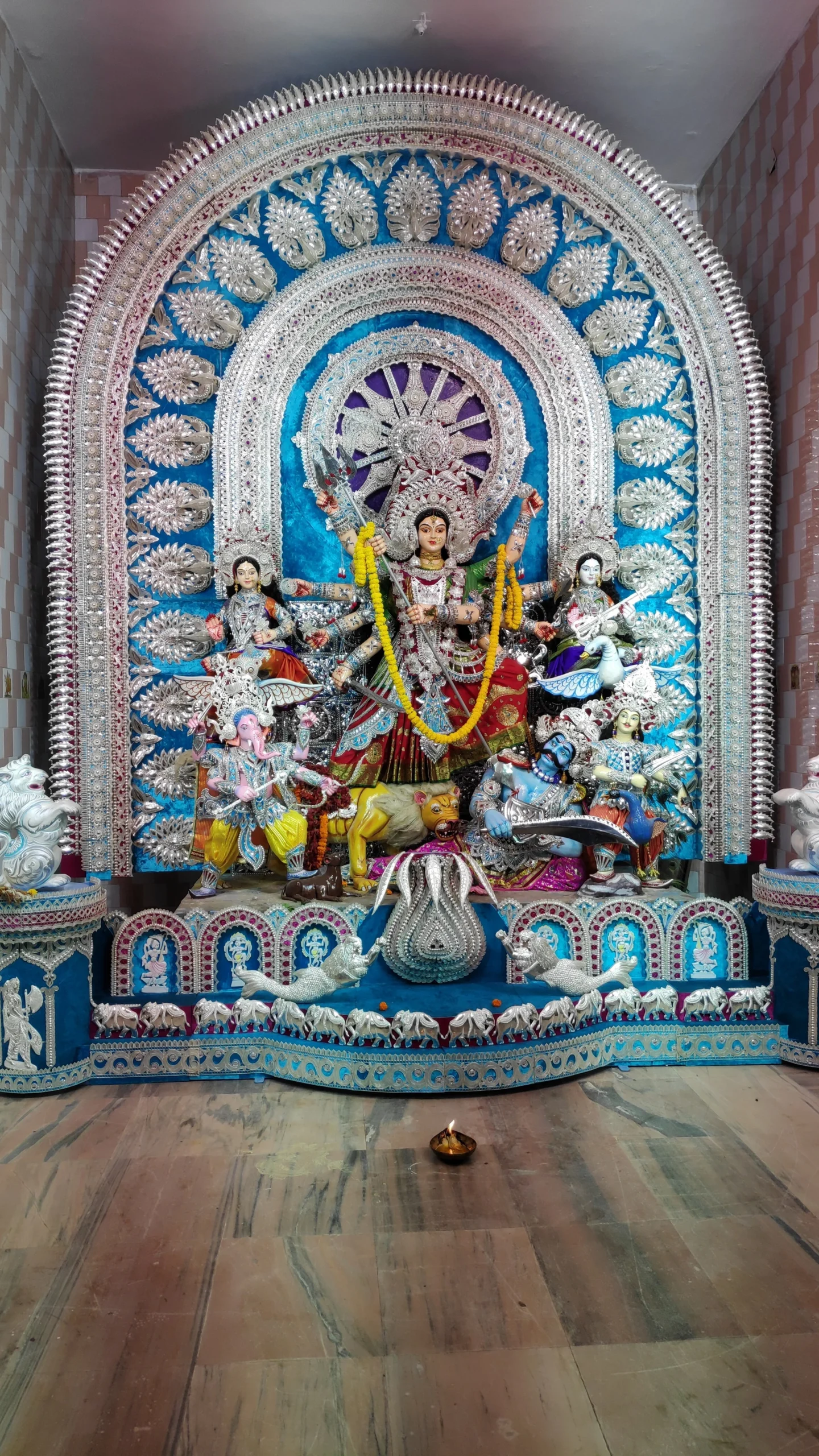 Intricate silver filigree Chandi Medha backdrop arch framing Goddess Durga at Kazi Bazar mandap in Kataka