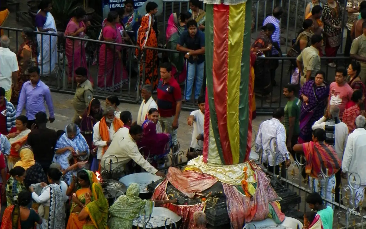 Pilgrims and devotees dressed in collared casual shirts, kurtas, and traditional sarees around Aruna Stambha at Puri Jagannath Temple
